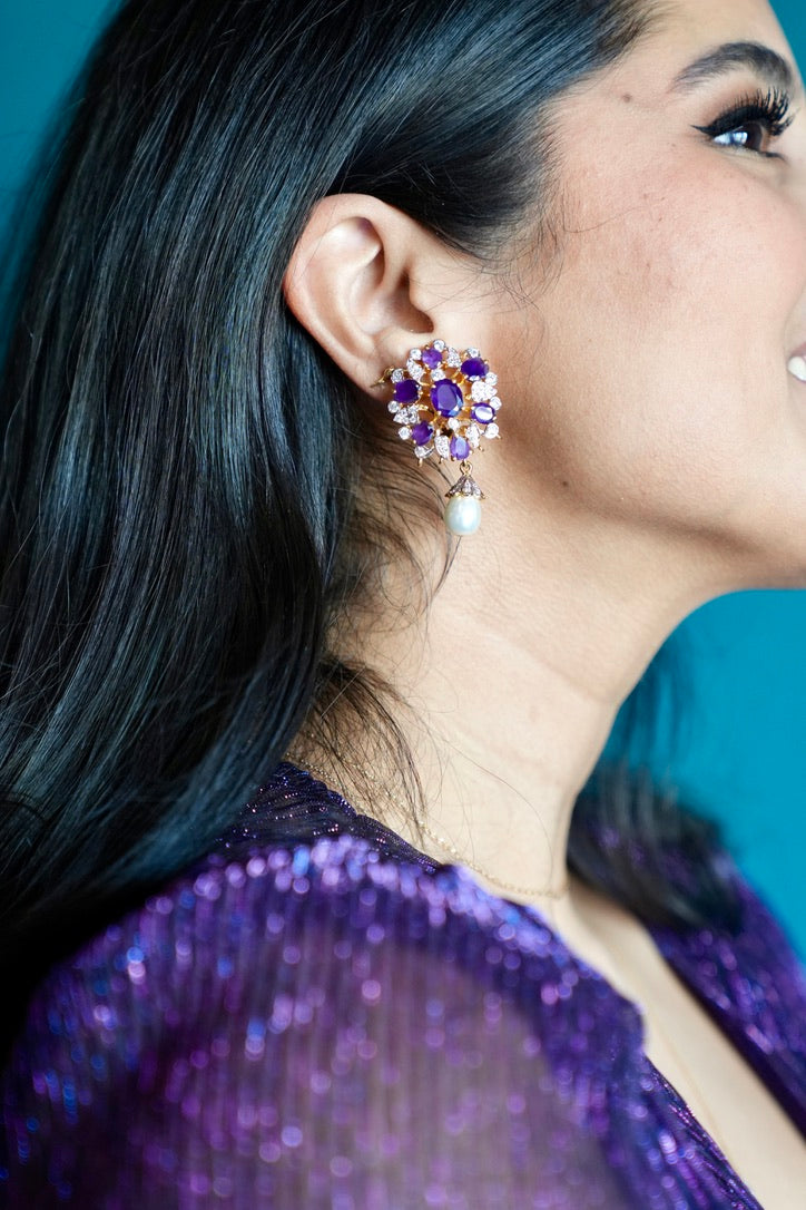 Close-up of a person wearing a sparkling earring against a blue background