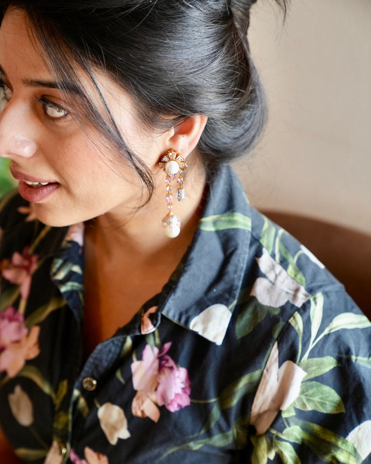 Woman wearing a floral top with a close-up of her earrings.