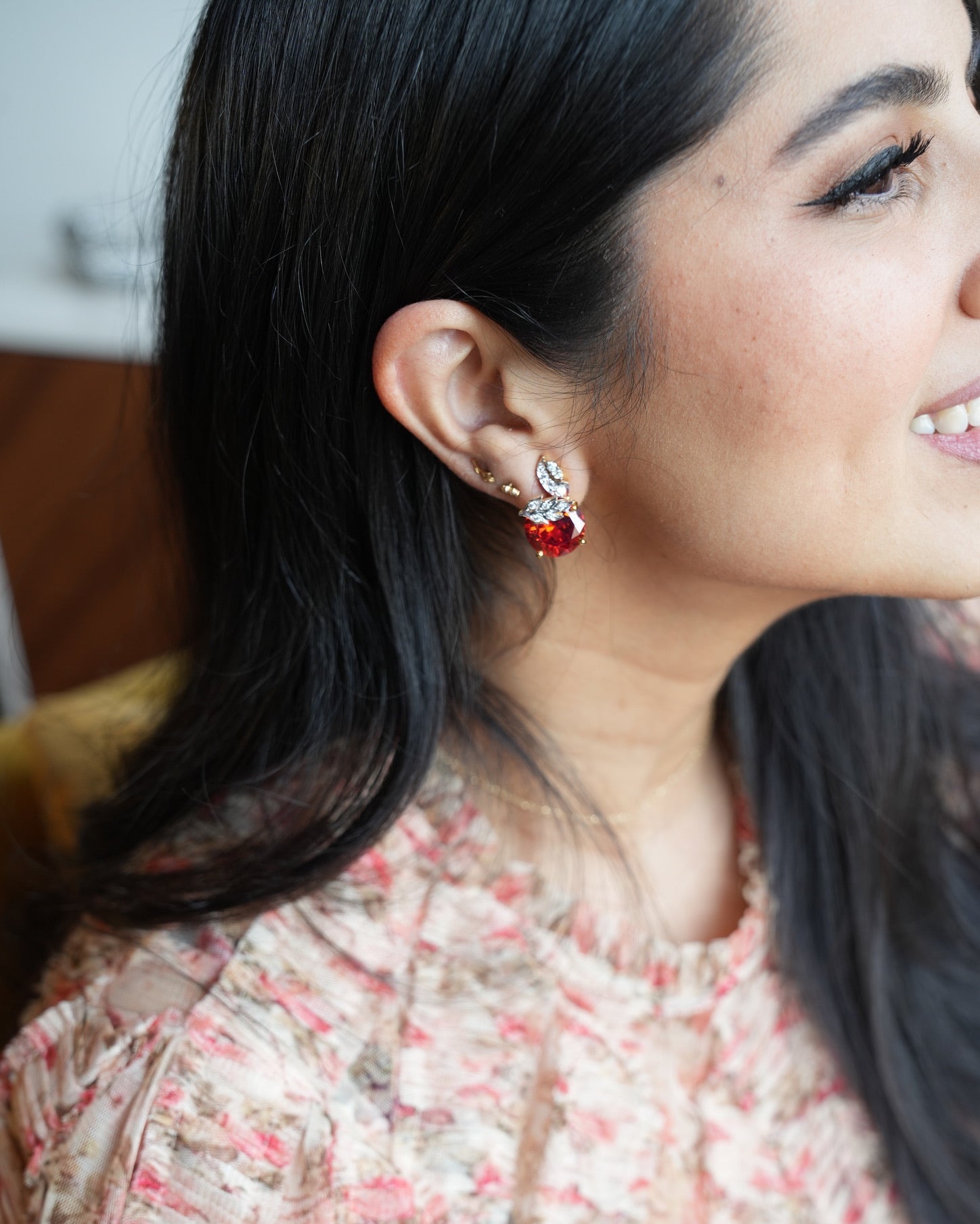 Close-up of a woman wearing red earrings with a blurred background