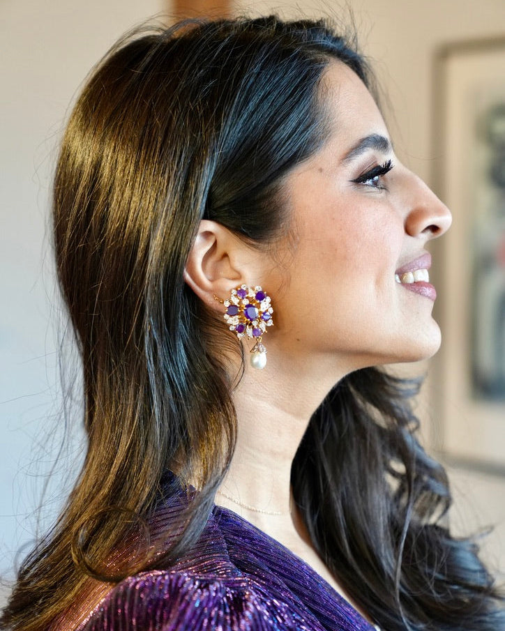 Woman wearing a purple sequin outfit and earrings with a blurred background