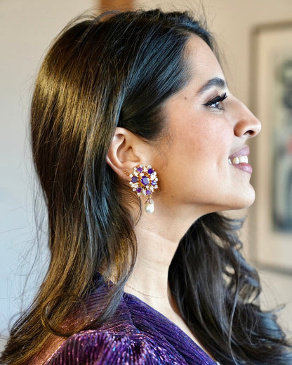 Woman wearing a purple sequin outfit and earrings with a blurred background